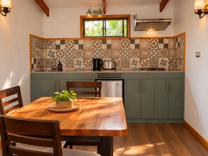 A kitchen with a wooden table, chairs, a window, and patterned backsplash. - Comfortable and equipped cabin (Isla de Pascua)