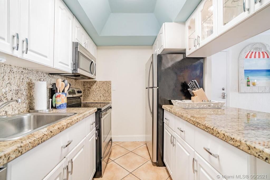 A kitchen with granite countertops, stainless steel appliances, and white cabinetry.