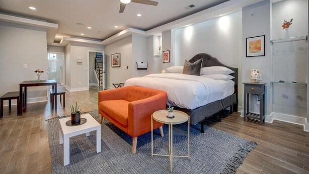 Een moderne slaapkamer met een groot bed, een plafondventilator, een tafeltje en een stoel.