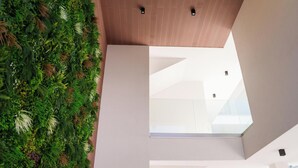 A modern interior with a large glass window and a green plant wall. - Welcomely - Seamphony Suite vista Tavolara (Olbia)