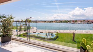 Un balcon avec vue sur un port de plaisance, un espace de jeux pour enfants et un cactus.