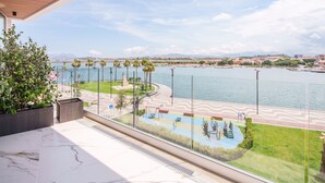 A balcony with a view of a waterfront promenade, including a playground and a marina. - Welcomely - Seamphony Deluxe Room (Olbia)