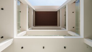 A modern interior with a central wooden panel, glass walls, and recessed lighting. - Welcomely - Seamphony Deluxe Room (Olbia)