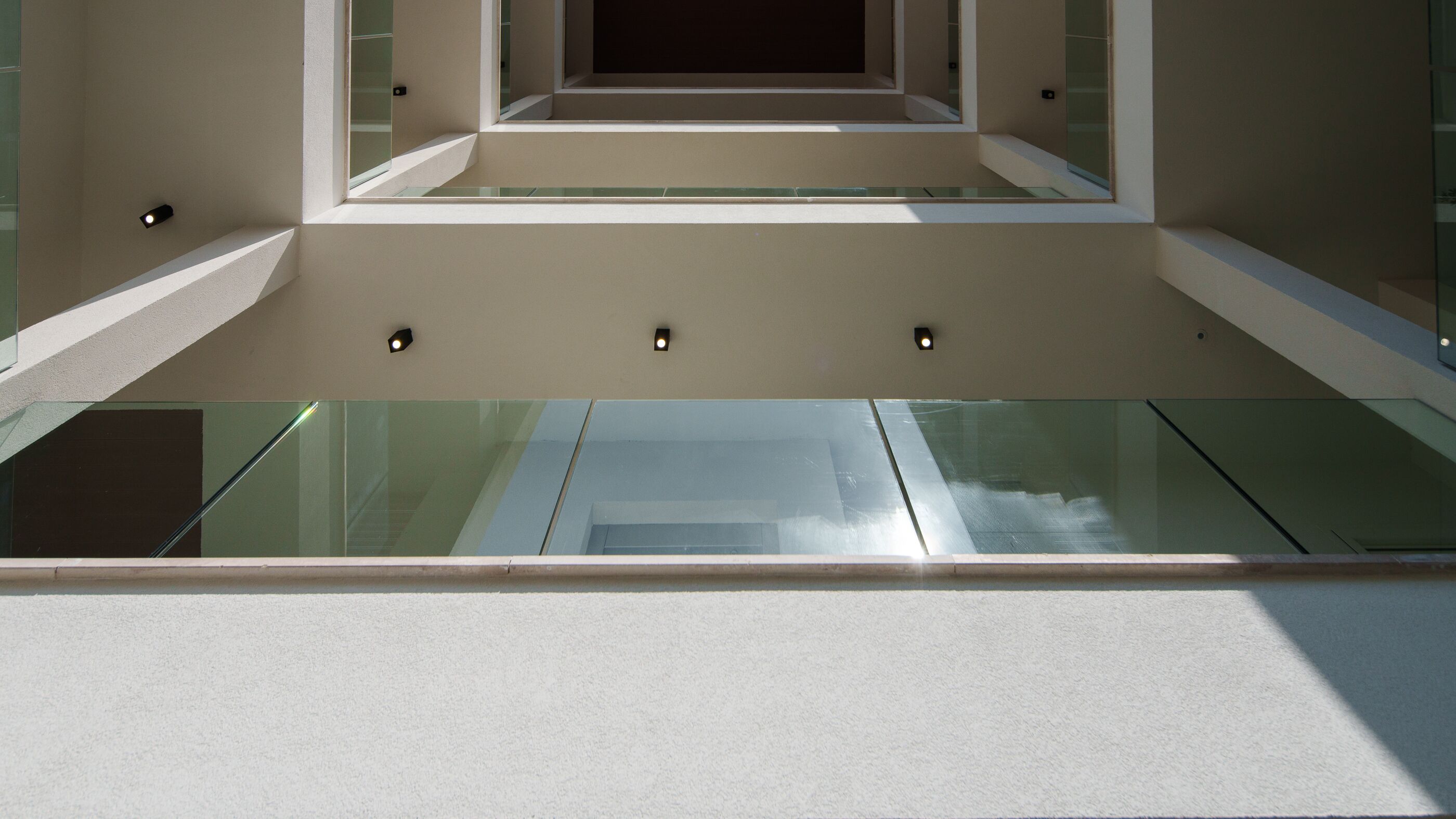 A modern architectural design with a glass floor and walls, recessed lighting, and a clean, minimalist aesthetic.