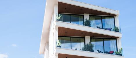 Un edificio moderno de varios pisos con balcones, ventanas amplias y plantas en macetas.