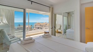 Ein Hotelzimmer mit Bett, Sessel, kleinem Tisch und Meerblick.