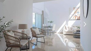 A spacious living room with a high ceiling, a dining area, and a sofa set.