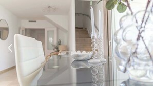A modern dining area with a glass table, white chair, and a decorative vase.