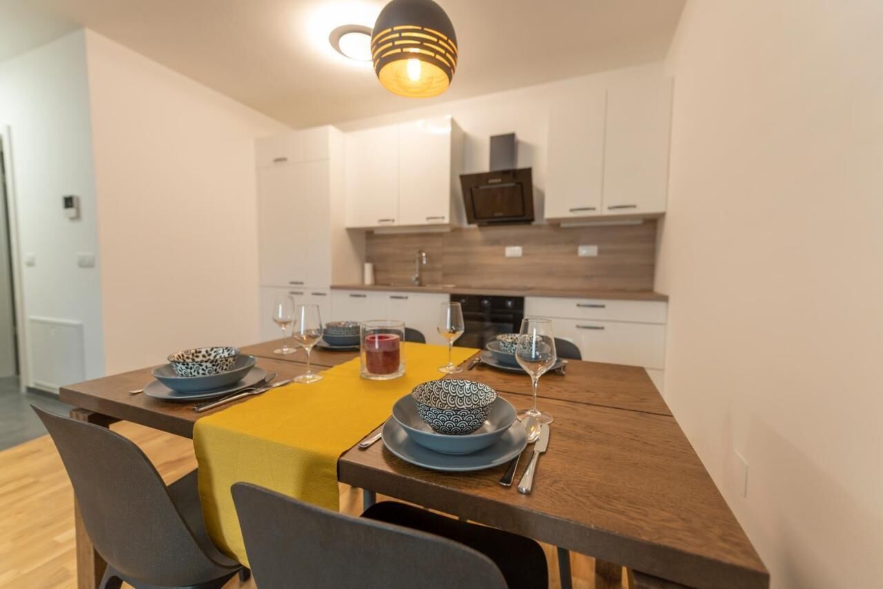 A modern kitchen with white cabinets, a wooden countertop, and a yellow tablecloth.