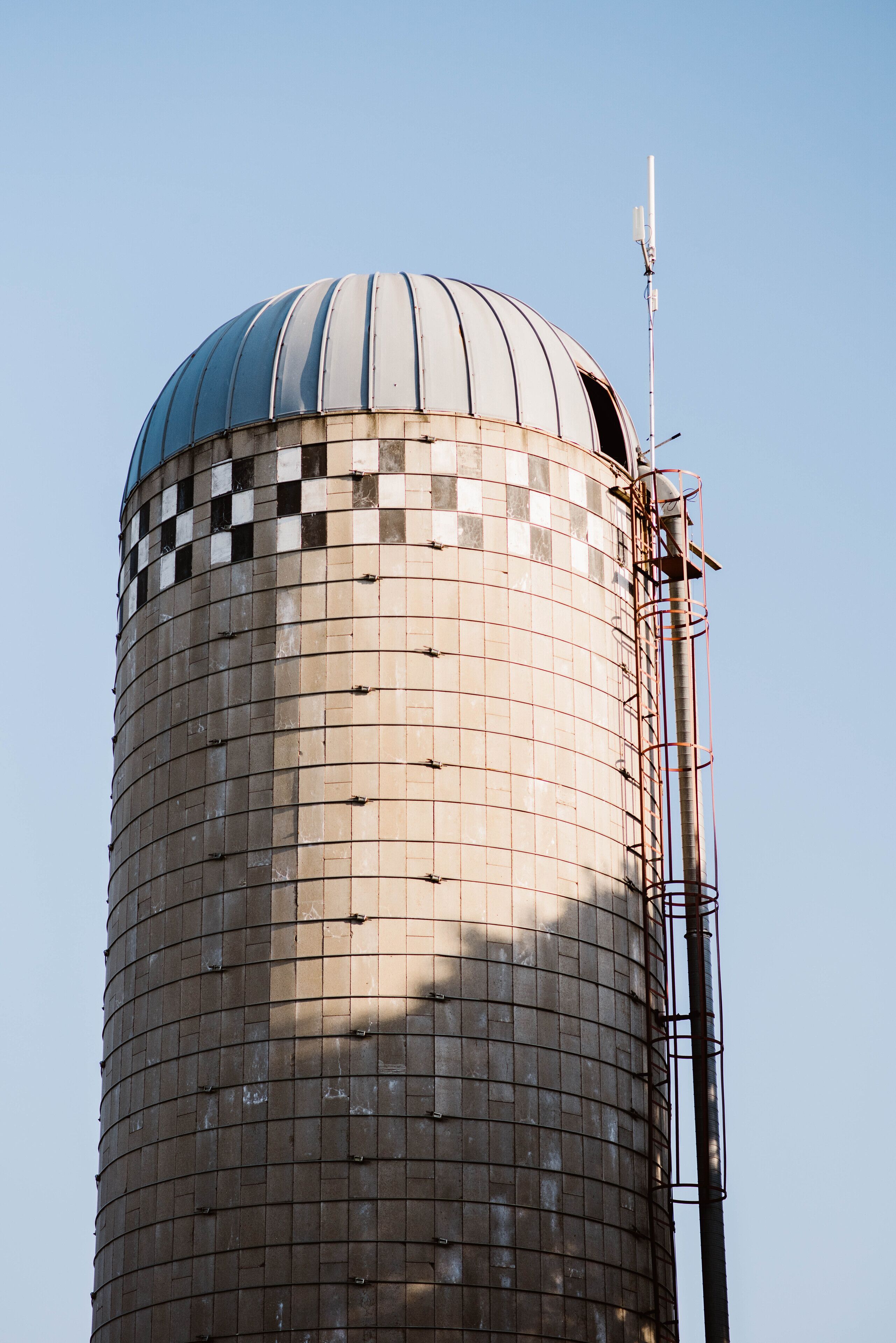 Una estructura cilíndrica con cúpula, que presenta un patrón tipo rejilla y una antena metálica a la derecha.