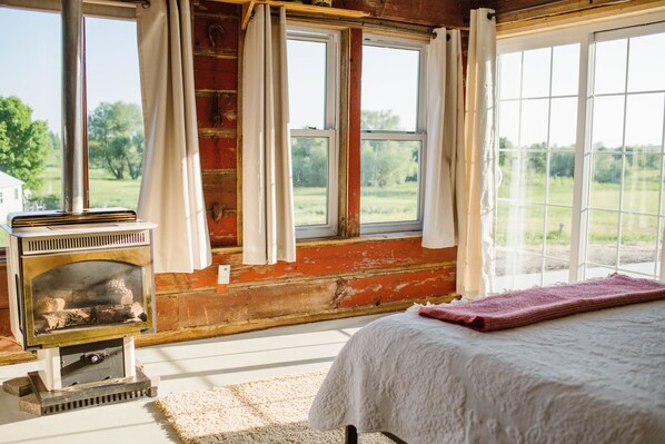 A bedroom with a fireplace, large windows, and a view of the outdoors.