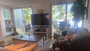 A living room with a sofa, coffee table, and TV. There are decorative items and a plant.