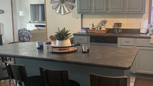 A kitchen with a central island, bar stools, and a decorative windmill on the wall.