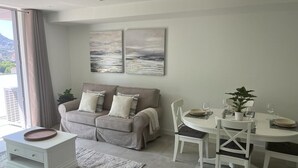 A modern living room with a sofa, a dining table with chairs, and a small side table.