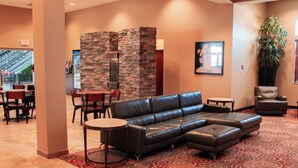 A lobby with a leather sofa, a stone wall, a large plant, and a patterned carpet.