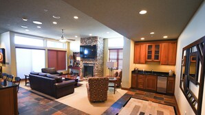 A spacious living area with a fireplace, a television, and a kitchen with wooden cabinets.