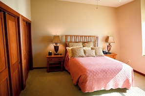A bedroom with a bed, two bedside tables, a nightstand, a wooden wardrobe, and a window.