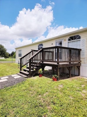 A single-story mobile home with a wooden deck and a small porch. - Mo's Lake "O" Retreat (Clewiston)