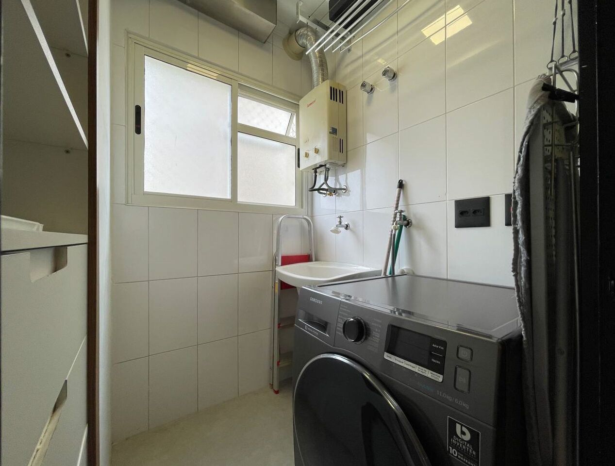 A compact laundry room with a washing machine, a sink, and a window.