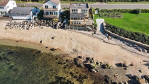 A coastal property with a large house, a smaller building, and a landscaped garden.