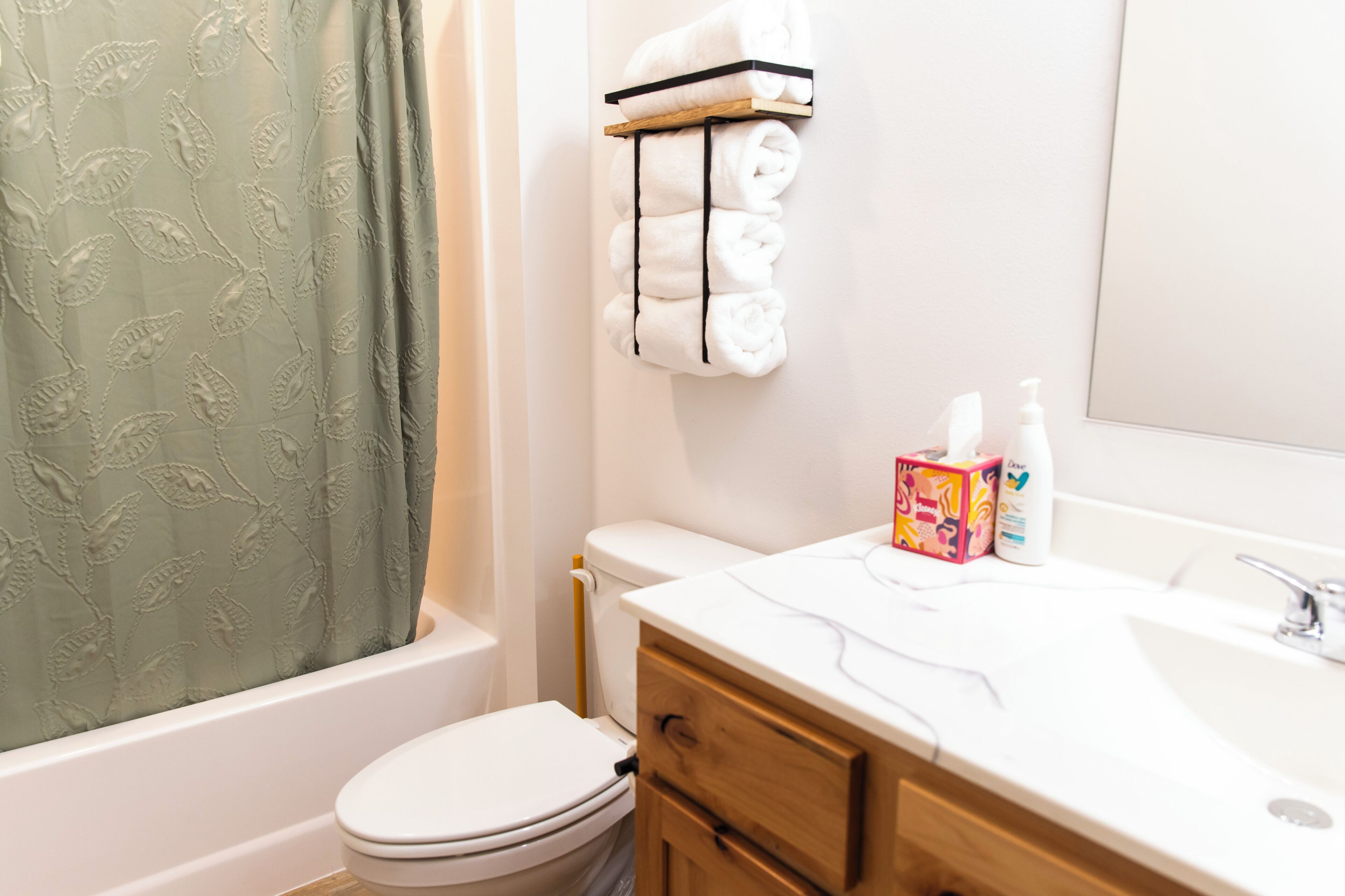 A bathroom with a toilet, a sink with toiletries, and a shower curtain.