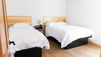 A bedroom with two beds, a nightstand, and a wooden headboard.