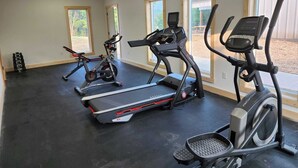 A gym with treadmills, elliptical machines, and a weight stack. - Bluffside Gardens (Decorah)