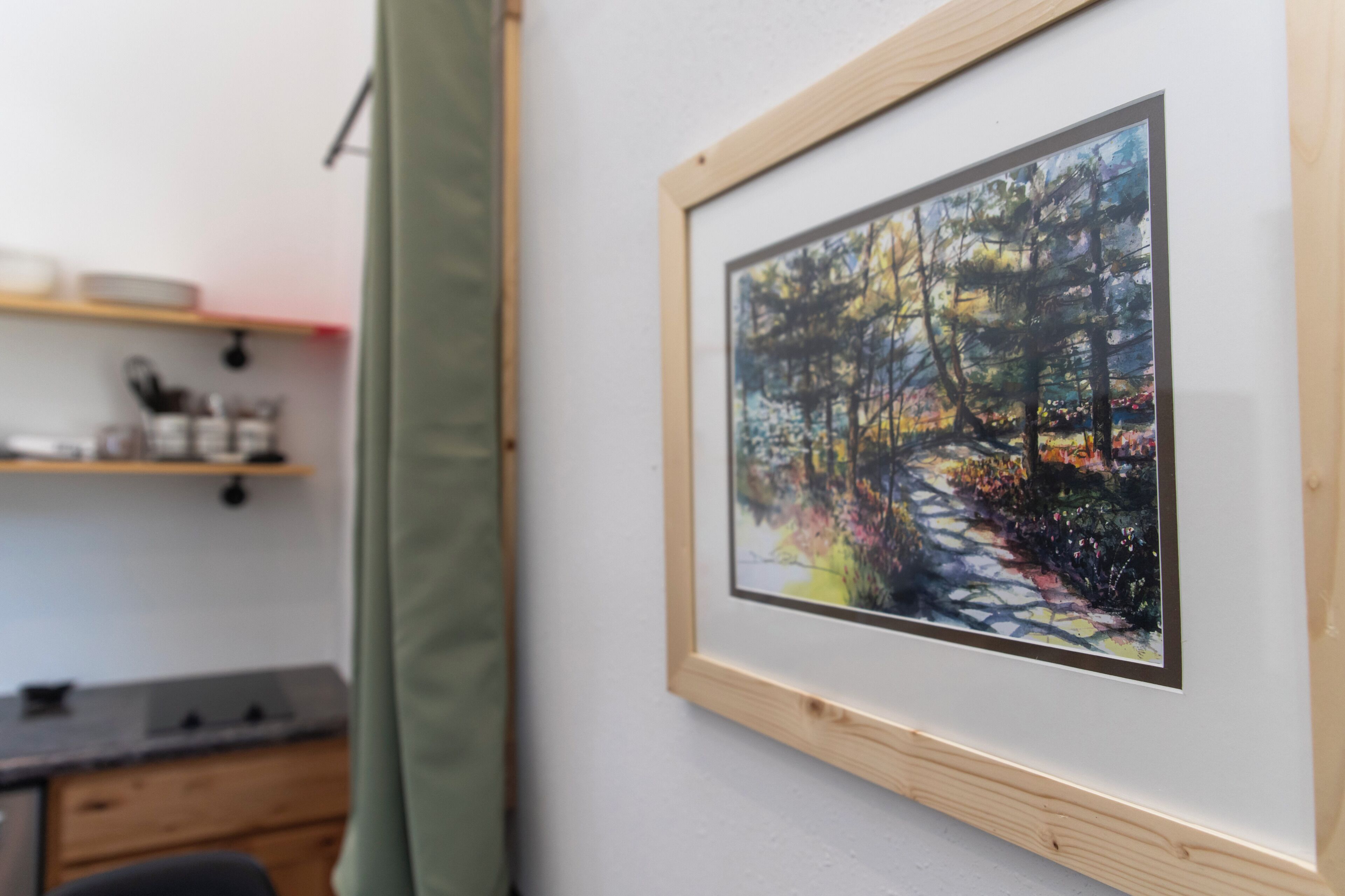 A framed painting of a forest path on a wall.
