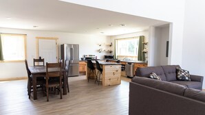A modern kitchen with a central island, wooden dining table, and chairs. - Bluffside Gardens (Decorah)