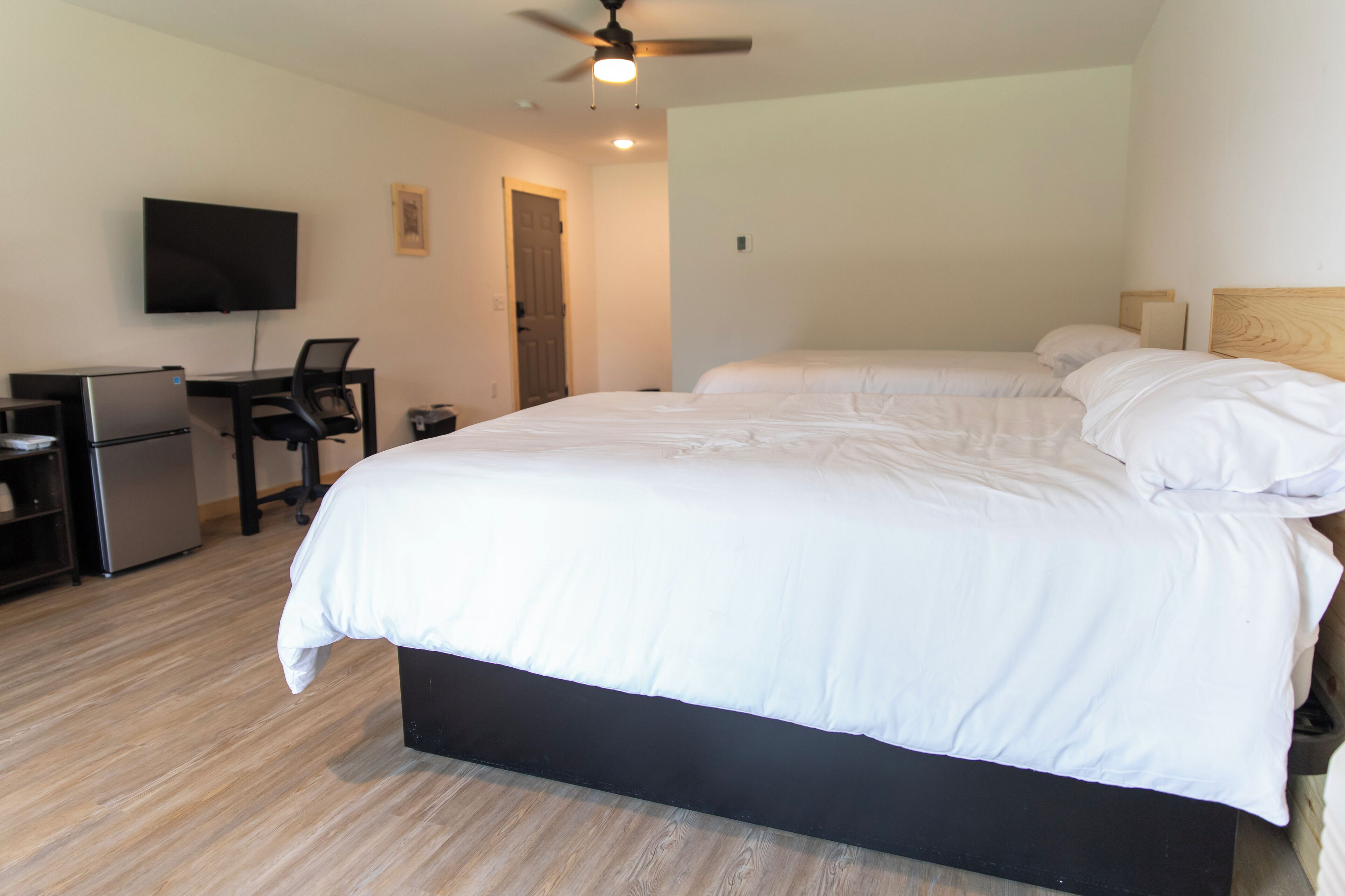 Une chambre d’hôtel équipée d’un lit, d’un bureau, d’une chaise, d’une télévision et d’un ventilateur de plafond.