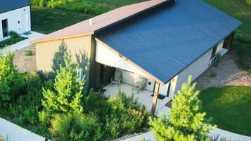 A modern house with a sloped roof, a covered patio, and a well-maintained garden.