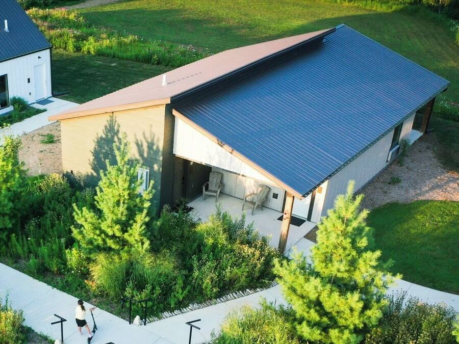 A modern house with a sloped roof, a covered patio, and a well-maintained garden.