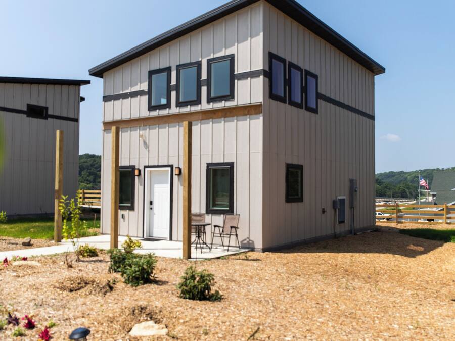 Un bâtiment moderne à deux étages, doté d’un toit plat, de grandes fenêtres et d’un patio couvert.