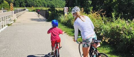 Un sendero pavimentado con un ciclista y un niño montando un triciclo.