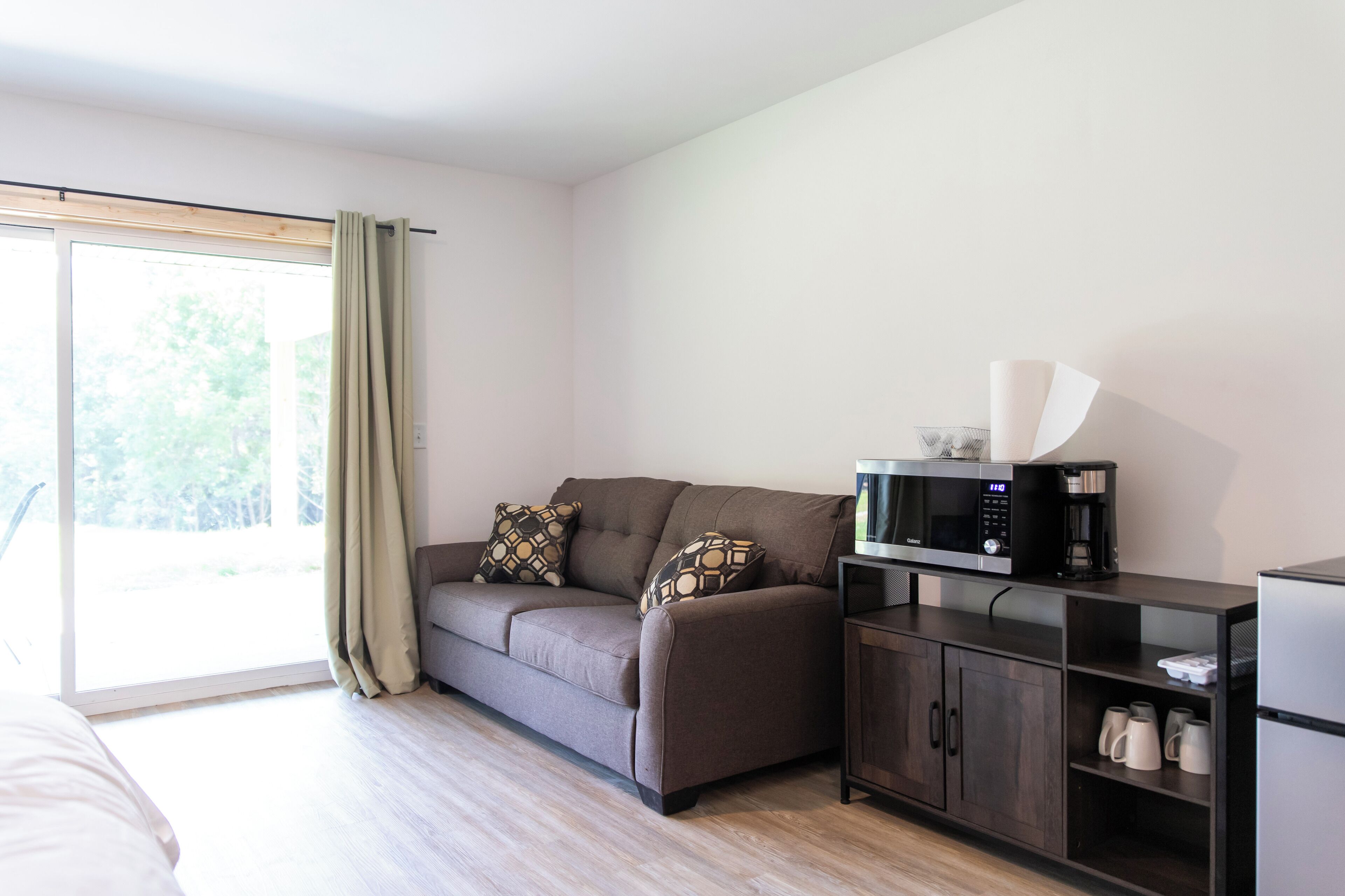 A modern room with a sofa, a coffee machine, a microwave, and a cabinet.
