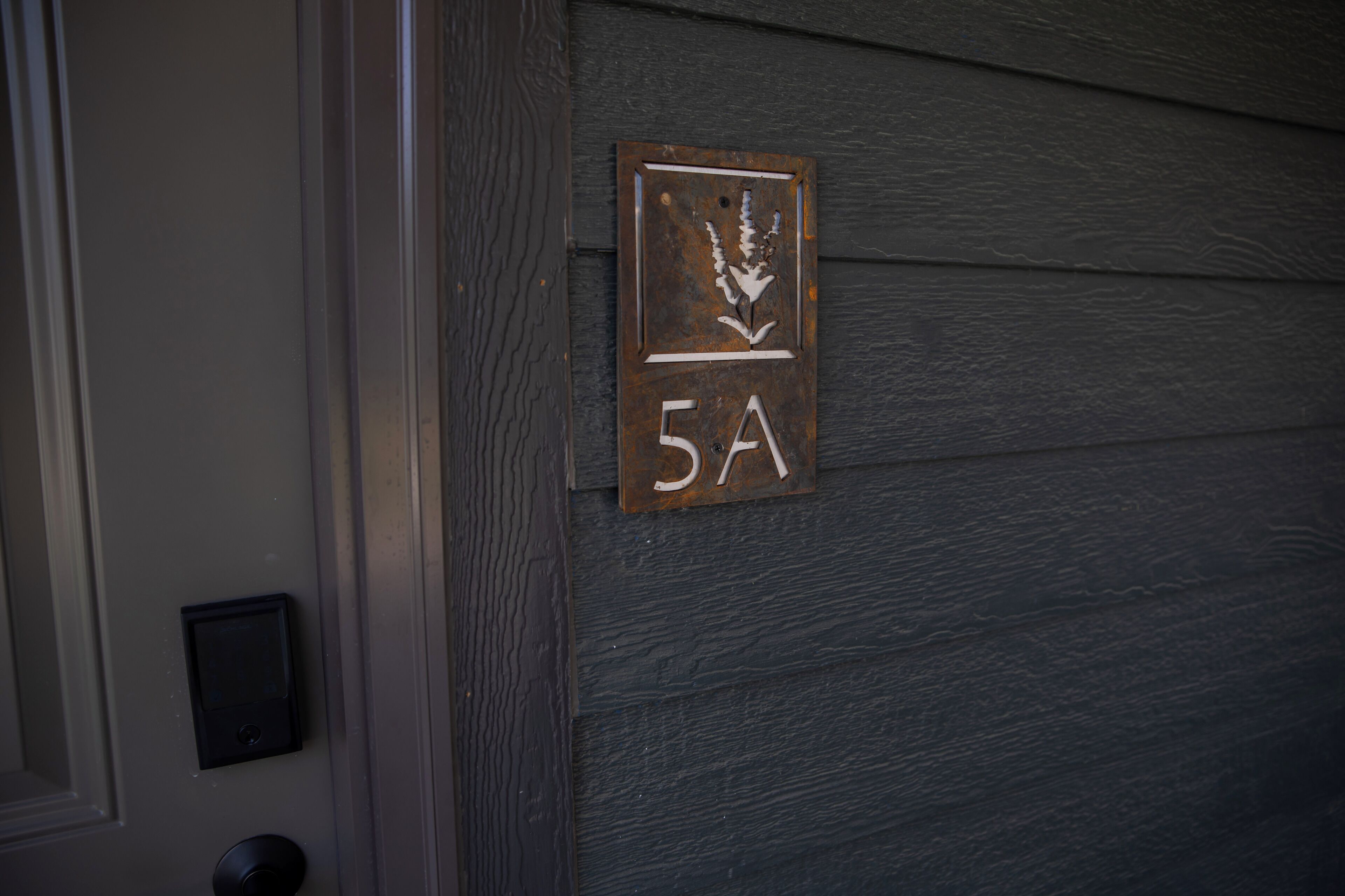 A house number plaque on a dark wooden door.