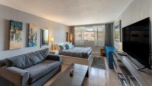 Una sala de estar moderna con sofá, cama, televisión y obras de arte en las paredes.