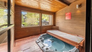Una cabaña de madera con jacuzzi, ventanas amplias y un letrero en la pared.