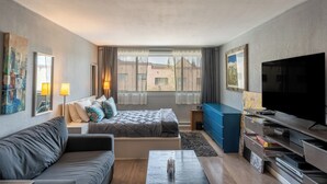 Una habitación de hotel moderna con cama, sofá, televisión y obras de arte en las paredes.