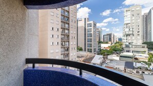 Blick vom Balkon mit Fliesenboden auf einen Stadtblick mit mehreren Hochhäusern und blauem Himmel.