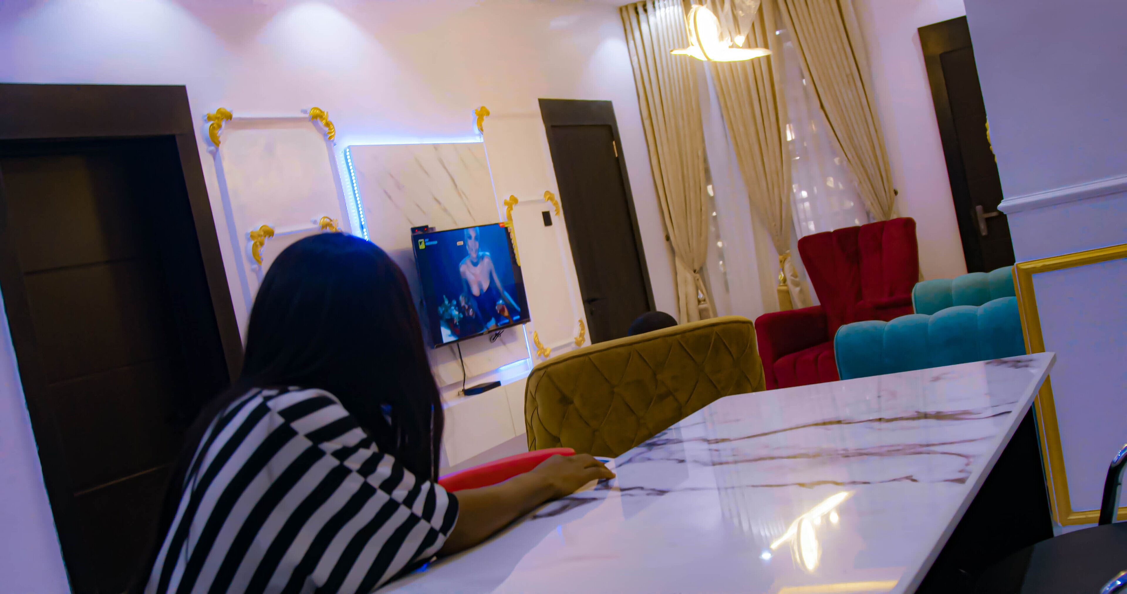 A room with a marble table, a television, and a mirror.