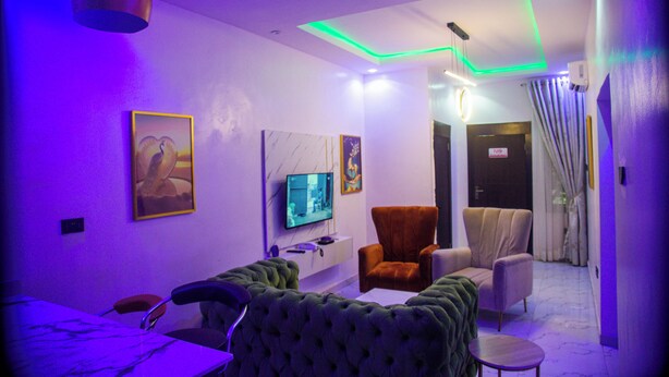 A modern living room with a flat-screen TV, comfortable seating, and ambient lighting. - RichVilla Apartments & Hotels (Lagos)
