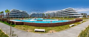 A modern hotel with a central pool, palm trees, and a clear sky. - Choco | Pool - Frontline Beach - plunge pool (Torremolinos)