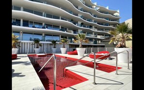 Ein modernes Hotel mit Poolbereich, roten Stufen und mehreren Balkonen.