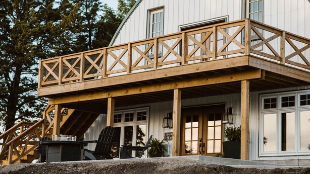 Een groot, wit gebouw met een houten terras en een overdekte veranda.