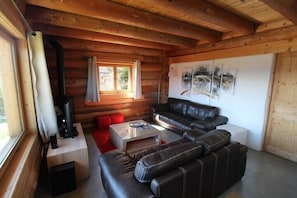 A wooden cabin interior with a sofa, a small table, and a window.