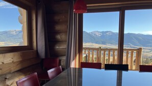 A wooden interior with a glass table and red chairs, overlooking a mountainous landscape. - Chalet L'estaca: Vue sur la Nature (Font-Romeu-Odeillo-Via)
