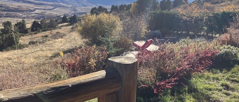 A wooden deck overlooking a mountainous landscape with autumn foliage.