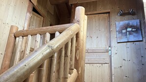 A wooden staircase leading to a room with a wooden door and a small shelf with two items on it. - Chalet L'estaca: Vue sur la Nature (Font-Romeu-Odeillo-Via)