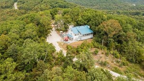 Uma casa com telhado azul, rodeada por uma floresta densa.